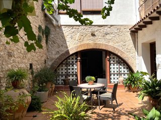 Patio romántico de Ca Roc con vegetación y piedra del siglo XVII