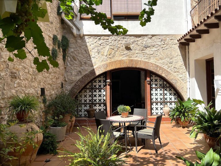 Patio romantico de Ca Roc con vegetacion y piedra del siglo XVII