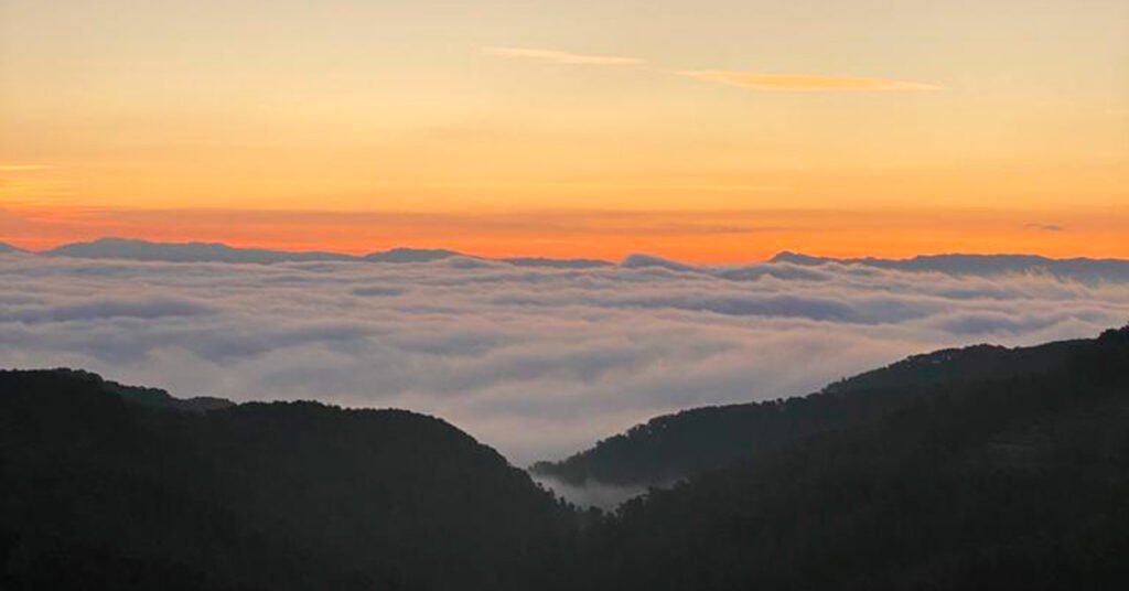 Mar de nubes cubriendo el valle entre montañas de Terra Alta al amanecer, con el cielo naranja característico de la comarca donde se vivirá el eclipse solar de 2026